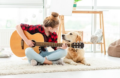 ギターを弾く女性と犬