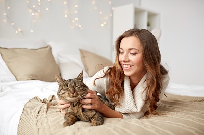 ベッドの上で猫を触る女性